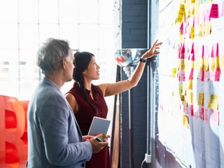 Man and woman looking at colorful adhensive notes on whiteboard