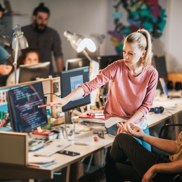 man and woman talking while looking at computer with data